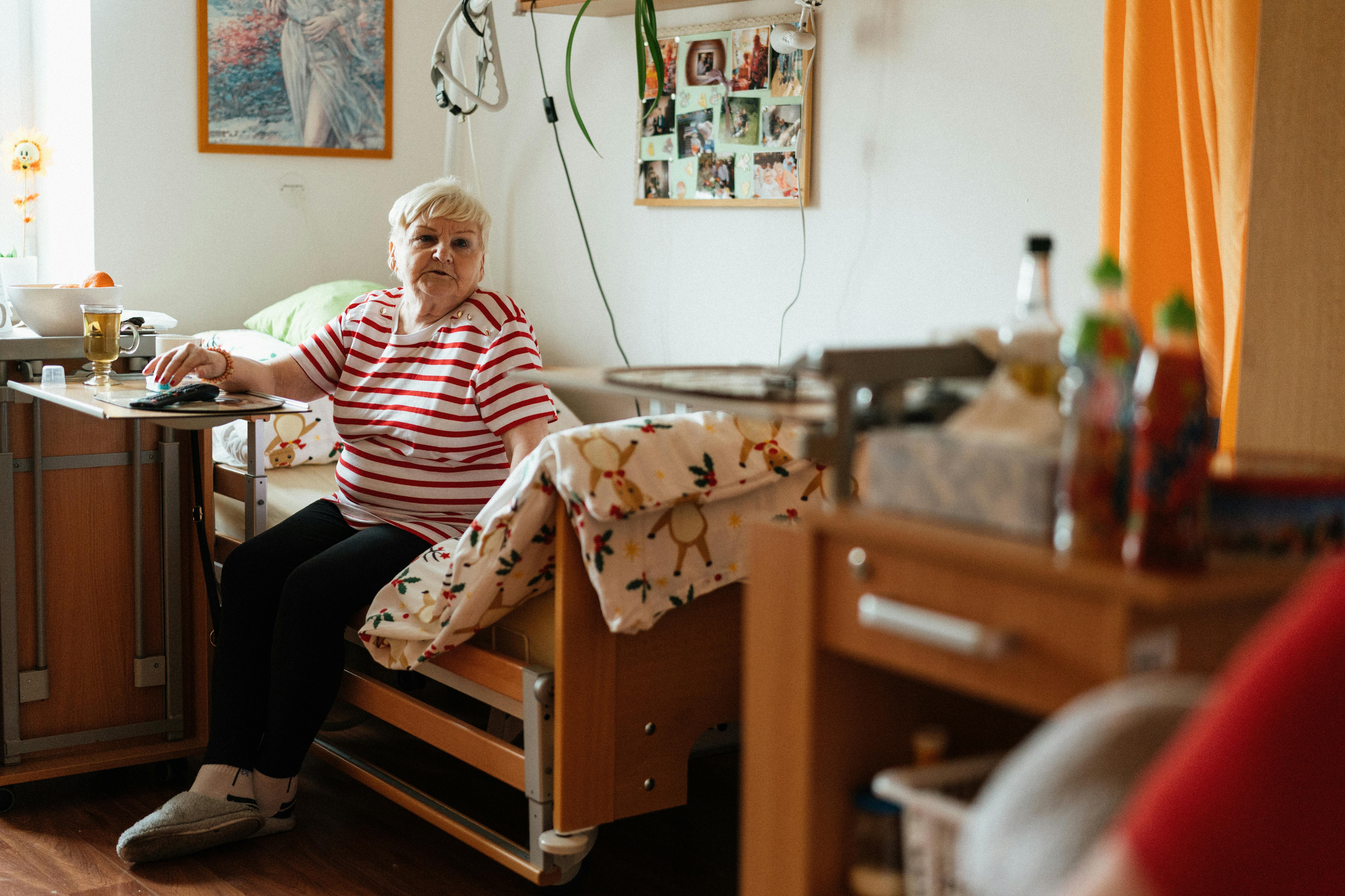 A senior in a care facility, watched over with dignity.